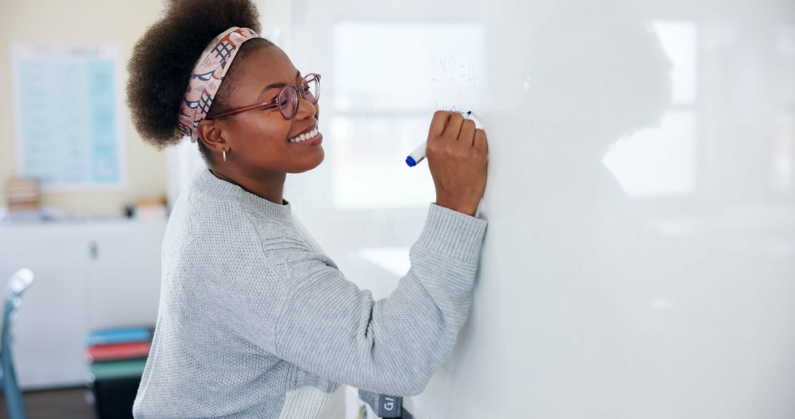 Teacher at whiteboard in classroom.