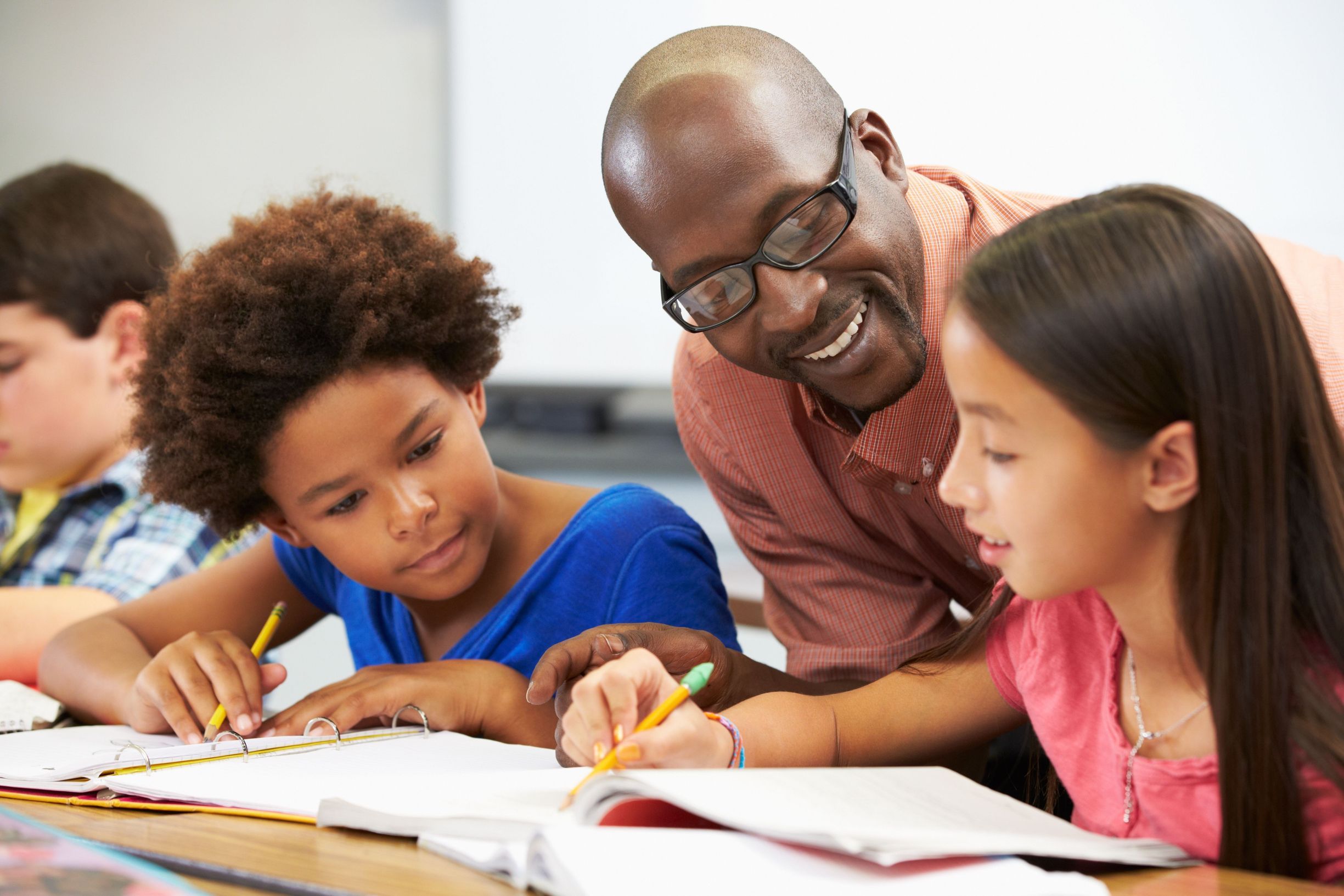 Teacher helping students study in classroom.